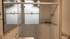 Un baño con lavamanos de mármol, ducha y espejo.