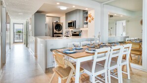 A modern kitchen with a central island, white cabinetry, and a dining area with wooden chairs.