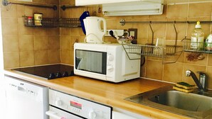 A compact kitchen with white cabinets, a microwave, a stove, and a dishwasher.
