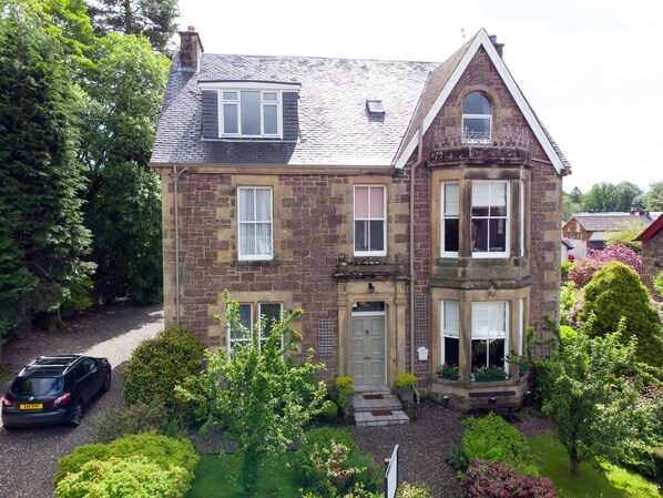 A two-story stone house with a traditional design, featuring a front entrance, a small porch, and a driveway. - Spacious Victorian House in Callander - perfect for family holidays. (Callander)