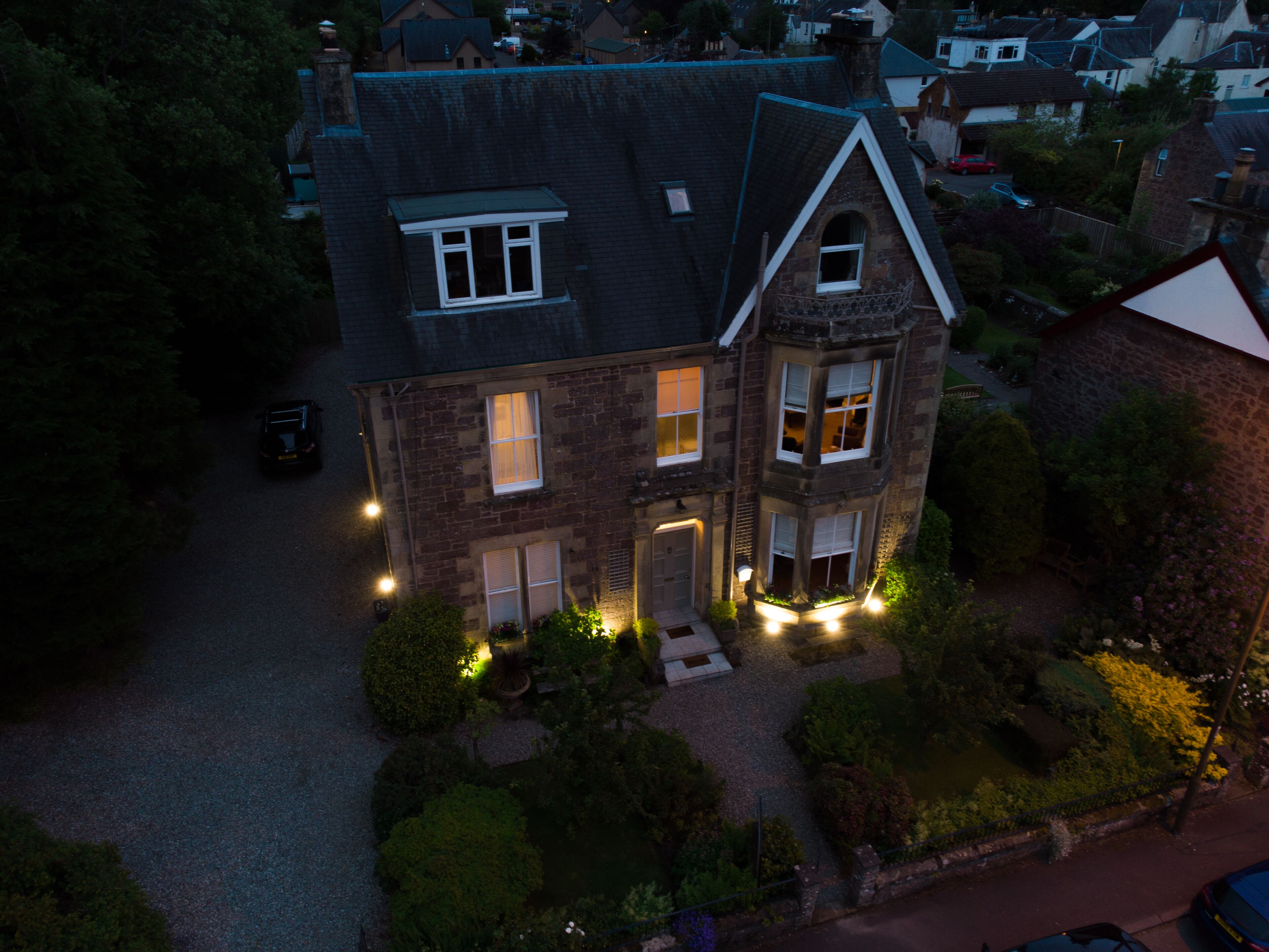 Une maison à deux étages, dotée d’un toit à forte pente, de nombreuses fenêtres et d’une cour avant bien éclairée.