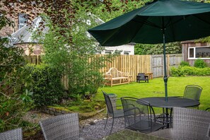 A patio with a table and chairs, surrounded by a wooden fence and greenery. - Spacious Victorian House in Callander - perfect for family holidays. (Callander)