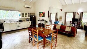 A spacious living area with a high ceiling, a dining table with chairs, a sofa, and a television. - Maison 79 – Your Private Soufrière Escape w/ 2BR, 2BA, AC & WiFi (Soufrière)
