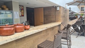A kitchen area with a countertop, a refrigerator stocked with beverages, and a door leading to another room. - GOLDFLAT CABO BRANCO JOÃO PESSOA (João Pessoa)
