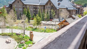 A multi-story hotel with a central courtyard, surrounded by trees and a mountain backdrop.