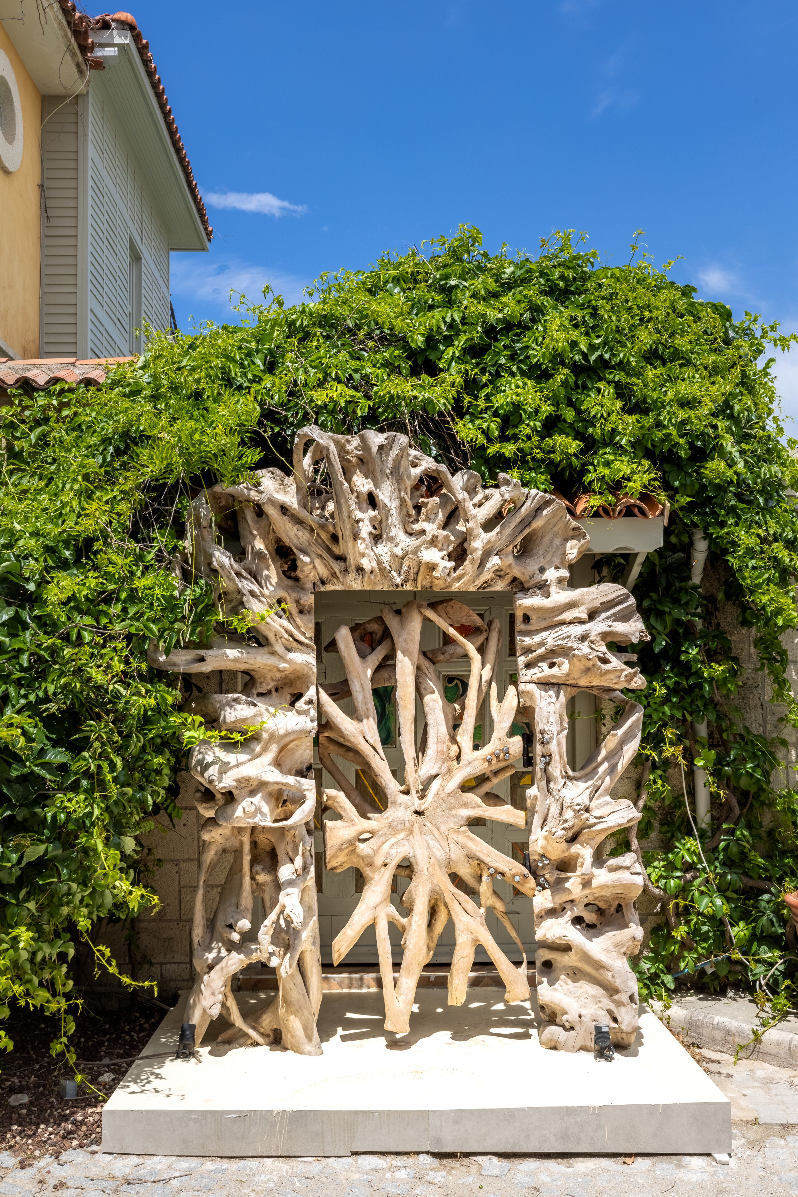 Une sculpture représentant des branches entrelacées, située dans un jardin.
