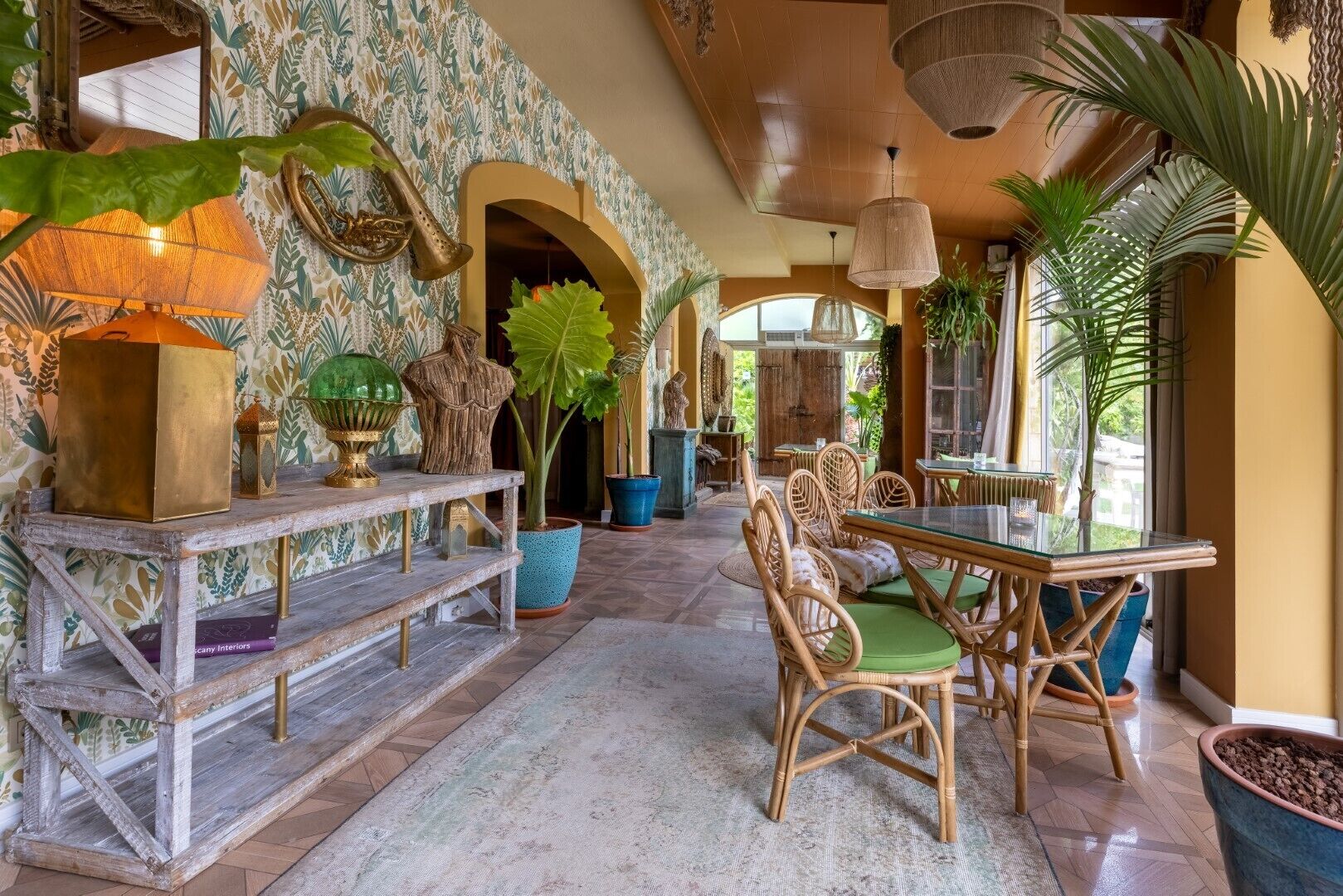 Una habitación amplia y luminosa con un banco de madera, una mesa de cristal y sillas de mimbre.
