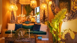 Un rincón acogedor con un sofá verde, lámparas decorativas y una mesa central con velas.