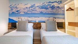 A room with two beds, a wooden headboard, a painting of a snowy landscape, and a wooden wardrobe. - Cilene del Fuego Suites & Spa (Ushuaia)