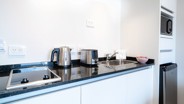 A modern kitchen with a black countertop, stainless steel appliances, a sink, and a built-in oven. - Cilene del Fuego Suites & Spa (Ushuaia)