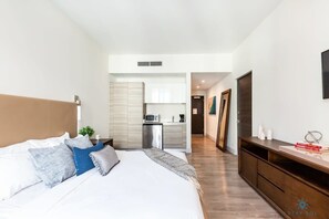 Relax in a serene space with a large bed, compact kitchen, and ample surface space.