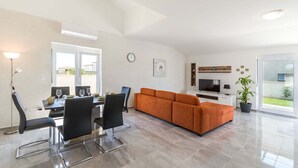 A modern living room with a dining area, a sofa, a TV, and a potted plant. - Villa Marino with private pool (Vodnjan)