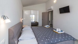 A modern hotel room with a bed, a bedside lamp, a flat-screen TV, and an air conditioning unit. - Villa Marino with private pool (Vodnjan)