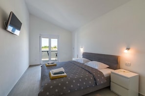 A bedroom with a bed, bedside tables, a TV, and a sliding door to an outdoor area.