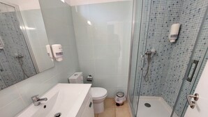A bathroom with a large white bathtub, a toilet, and a glass-enclosed shower area. - CASA da PRAIA ALBUFEIRA PORTUGAL (Albufeira)