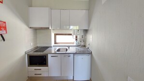 A compact kitchen with white cabinets, a built-in oven, a refrigerator, and a window above the sink. - CASA da PRAIA ALBUFEIRA PORTUGAL (Albufeira)