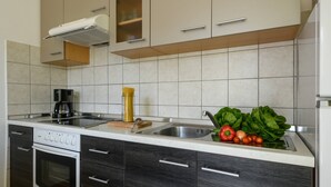 A modern kitchen with a built-in oven, a coffee maker, and a sink. - Apartment Matej (Rabac)