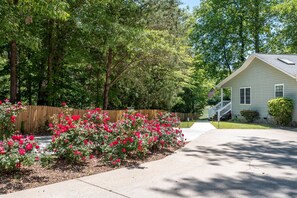 Situated in a well-maintained yard, this two-story house features a front door accessible via a small set of stairs.