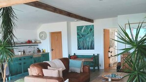 Een ruime woonkamer met een bruine leren bank, een houten salontafel en een groot schilderij aan de muur.