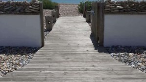 Een houten looppad dat naar een strand leidt, onder een heldere lucht.