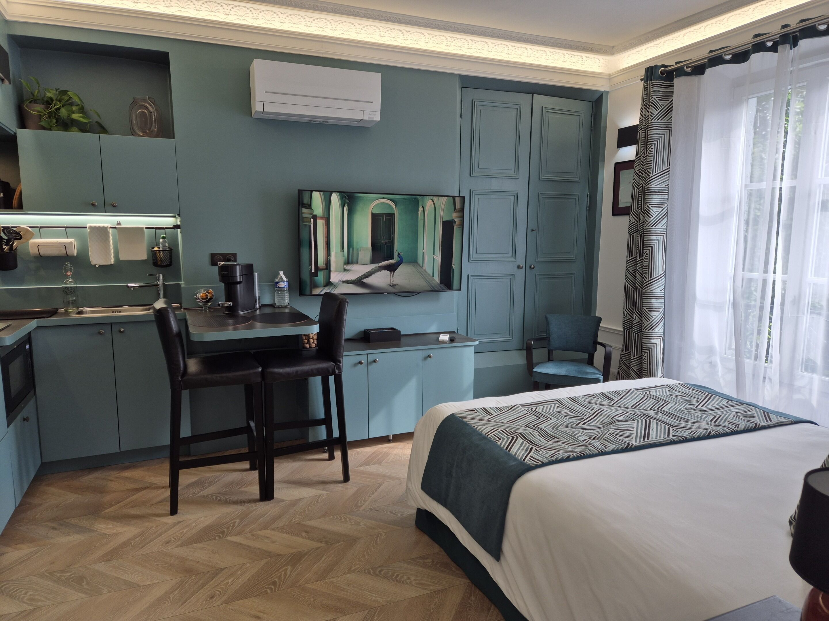 Una camera d'albergo moderna con un letto, una scrivania con una sedia, una televisione e un armadio.