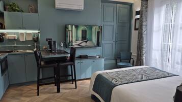 Una camera d'albergo moderna con un letto, una scrivania con una sedia, una televisione e un armadio.
