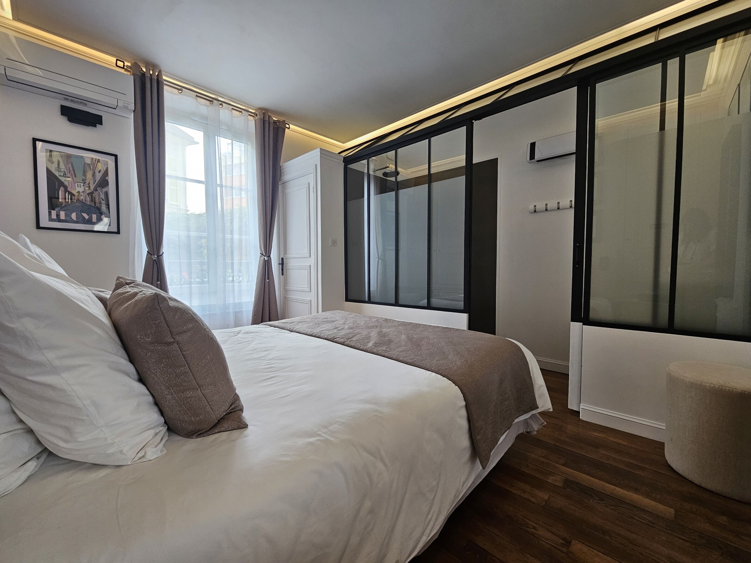 Een moderne slaapkamer met een groot bed, een inloopkast en een groot raam met gordijnen.