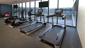 Uma academia com esteiras, elípticos e bicicleta ergométrica.