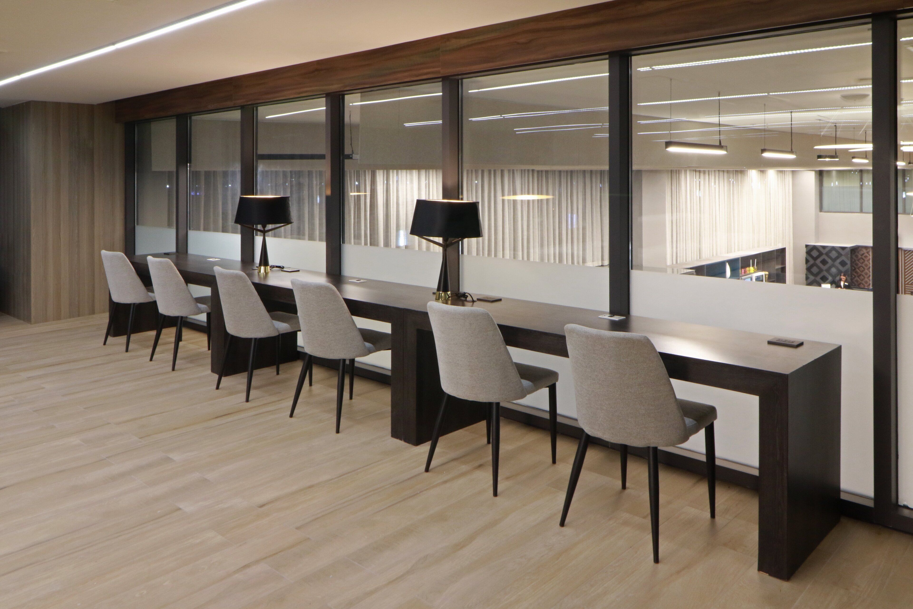 A modern conference room with a long table, six chairs, and two floor lamps.