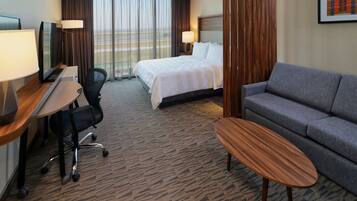 Habitación de hotel con cama, sofá, escritorio con computadora, silla y televisor.