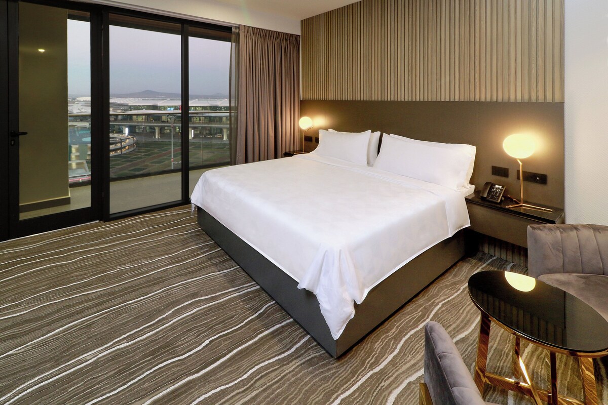 Une chambre d’hôtel avec un grand lit, une vue sur un pont et un panorama sur la ville.