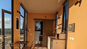Een kleine kamer met een bed, een tafeltje en een kitchenette.