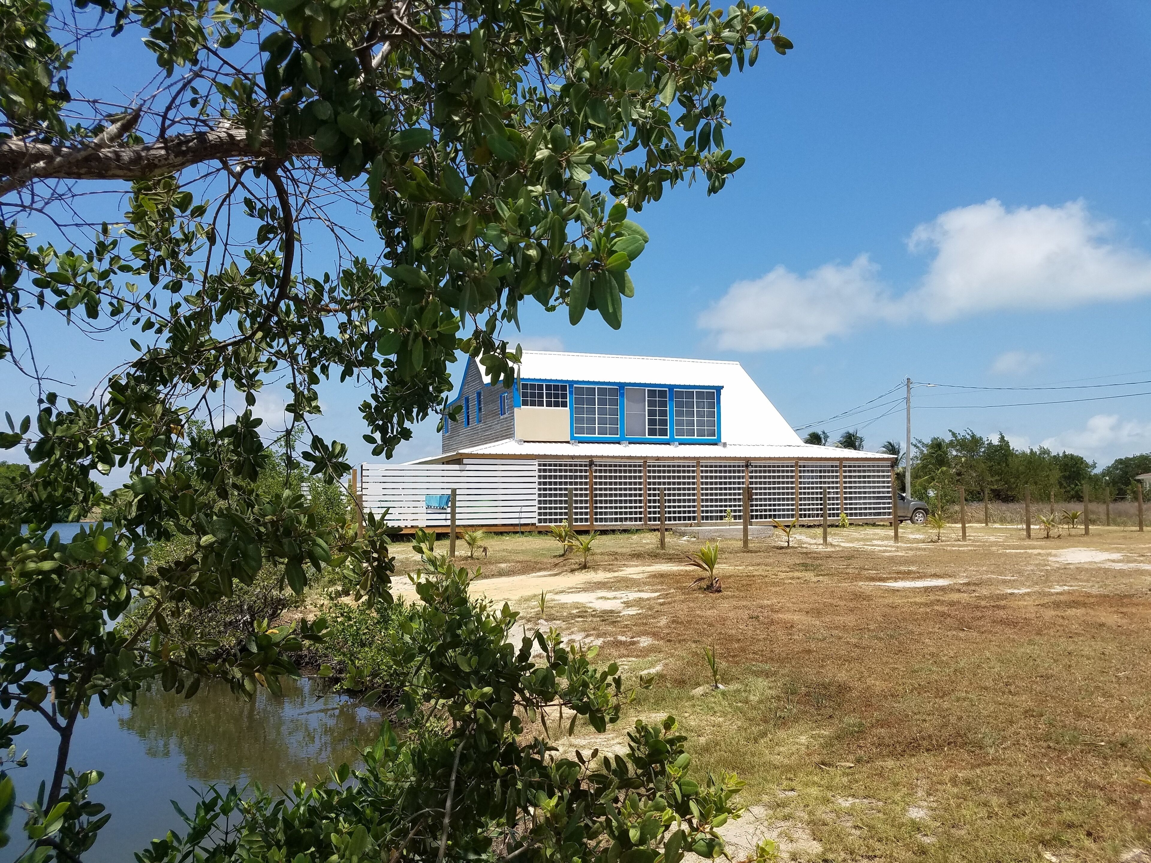 A modern house with a white and blue exterior, a large window, and a fenced yard.