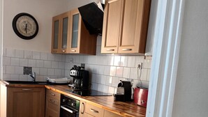 A kitchen with wooden cabinets, a coffee maker, and a dishwasher. - SEASONAL HOUSE RENTAL (Les Sables-d'Olonne)