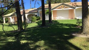 Ein Haus mit überdachter Terrasse, Garage und gepflegtem Rasen.