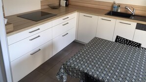 Eine kleine Küche mit Arbeitsfläche, Spüle und weißen Schränken.