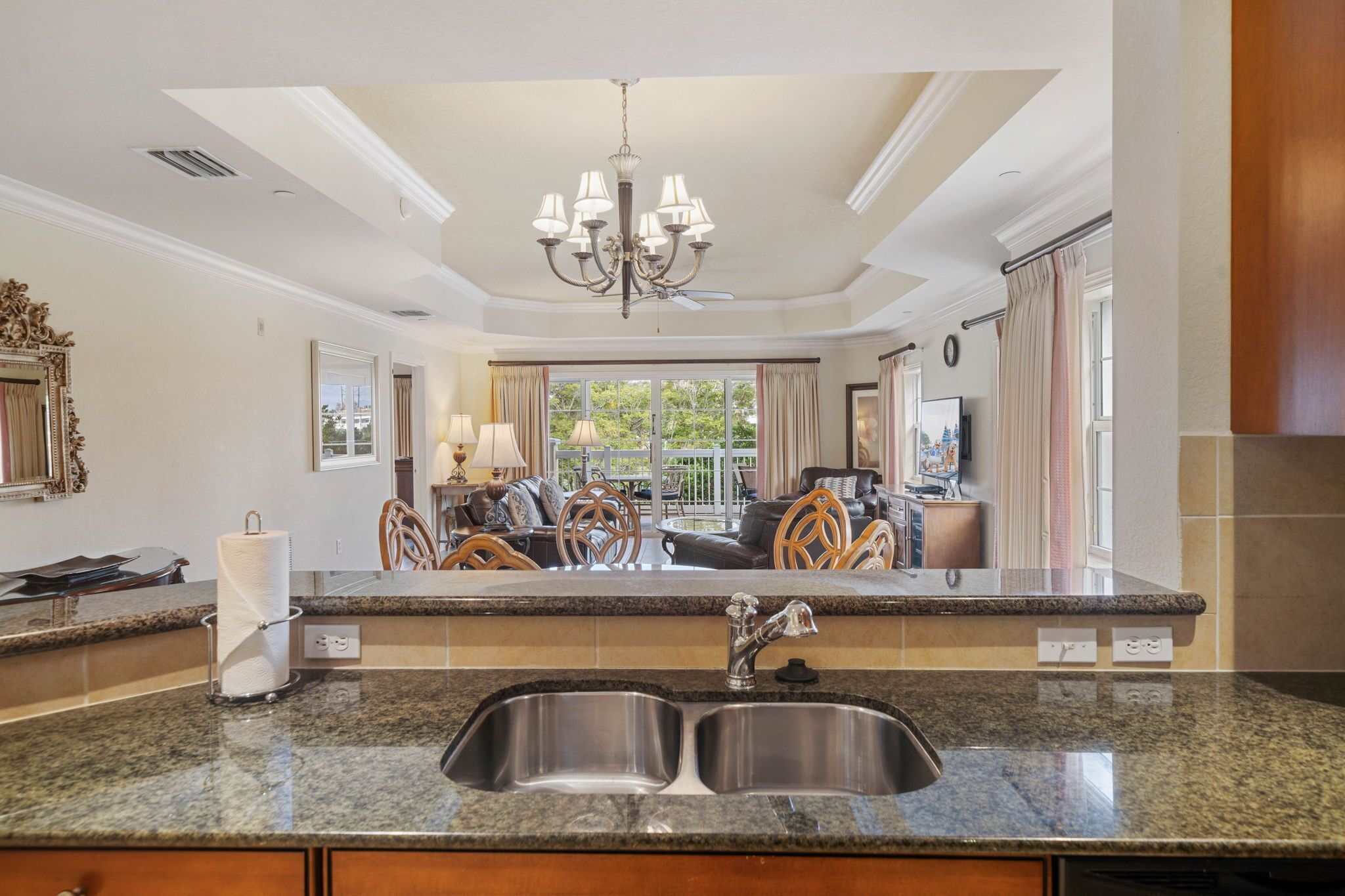 A modern kitchen with granite countertops, a double sink, and a chandelier.