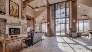A spacious lobby with a fireplace, stone walls, and large windows allowing natural light.