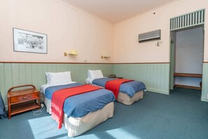 Classic hotel room with two single beds, a wooden nightstand, and a wardrobe.
