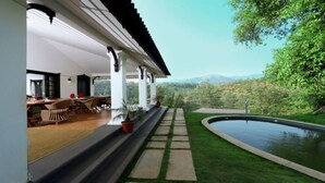 Un espace extérieur abrité comprenant une piscine, un coin repas et une vue sur le paysage environnant.