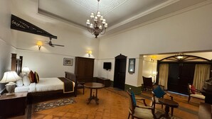 Une chambre d’hôtel comprenant un lit, une table de chevet, une lampe, une chaise et un coin repas avec une table et des chaises.