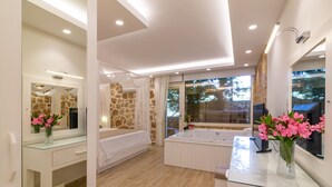 A modern bathroom with a glass-enclosed shower, a freestanding bathtub, and a vanity with a mirror and vase of flowers. - La Mer Comfort Kalkan (Kalkan - Kaş)