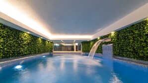 An indoor swimming pool with a waterfall feature, surrounded by green foliage walls, and a clear view into the adjacent room. - La Mer Comfort Kalkan (Kalkan - Kaş)