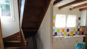 Eine Küche mit gefliestem Fliesenspiegel, einer Holztreppe und einem Fenster mit Vorhängen.