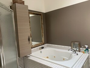 Une salle de bain avec une baignoire blanche, un meuble en bois et un miroir.
