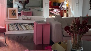 Een woonkamer met een bank, een salontafel, een boekenkast en een spiegel.