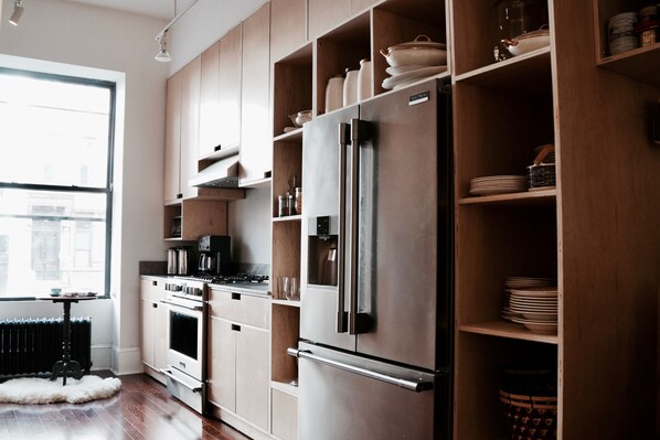 Une cuisine moderne avec des meubles en bois, un réfrigérateur en acier inoxydable et un four encastré.