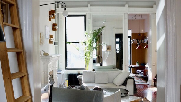Een ruime woonkamer met een witte bank, een houten tafel en een plafondventilator.