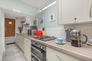 Uma cozinha equipada com fogão, micro-ondas, torradeira e cafeteira.