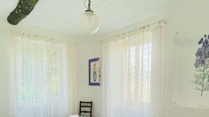 Una habitación con una cama, una silla, una mesa y un cuadro en la pared.